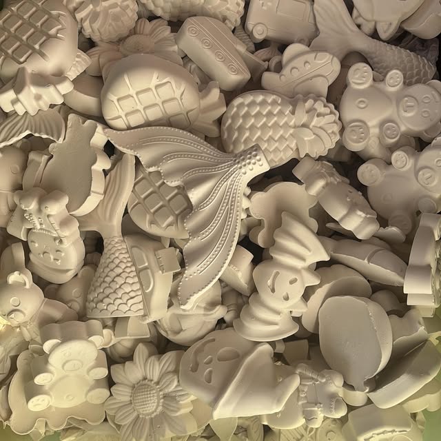 A pile of small plaster figures waiting to be packed: pineapples, bears, ice cream cones, and mermaid tails.